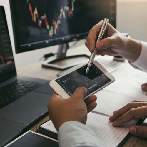 Two investors are working together to analyze the graph of the company shares that will grow on the mobile phone screen.