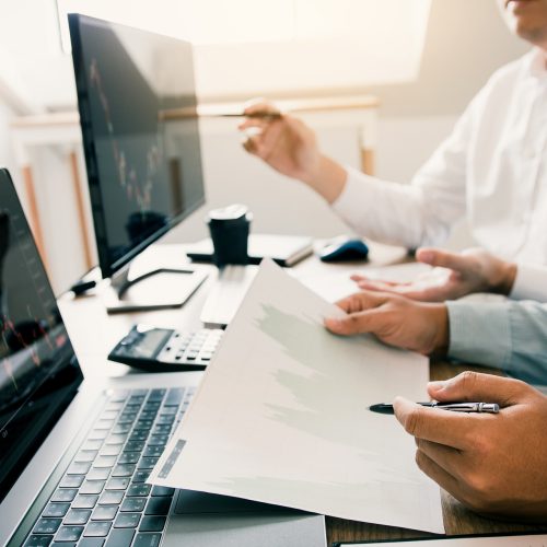 Two business stock brokers stress and looking at monitors displaying financial information.