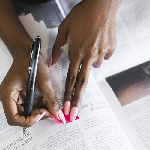 Black woman highlighting an article on the newspaper