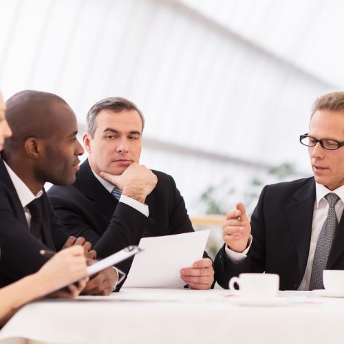 Business meeting. Business people in formalwear discussing something while sitting together at the table