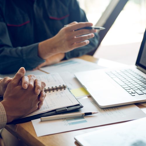 Businessman point to the graph of the company financial statemen Businessman point to the graph of the company financial statements report in the computer screen giving a presentation to colleagues in office room.
