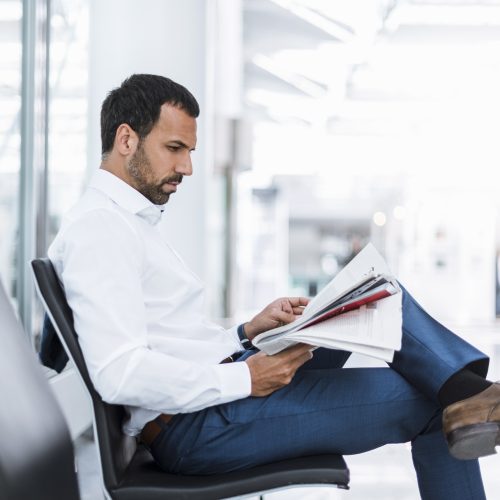 Businessman reading a newspaper in waiting hall Businessman reading a newspaper in waiting hall