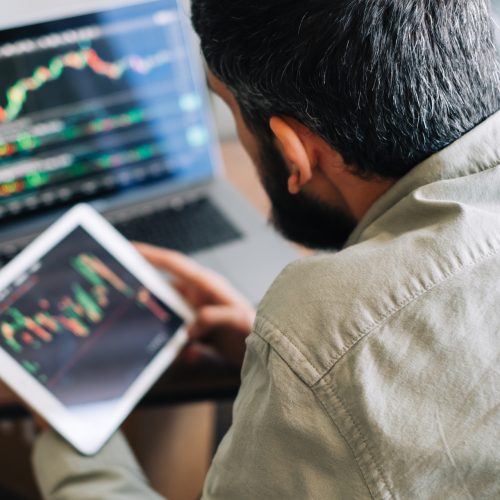 Caucasian businessman trading online, using computer technology, looking on stock exchange trade and analyzing