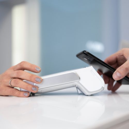 Customer paying by smartphone with NFC technology in POS terminal